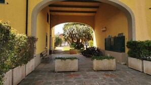 An arched corridor with a yellow wall, potted plants, and bicycles. - House by the sea, 2 km from Baratti gulf & Etruscan archaeological park (Stazione di Populonia)