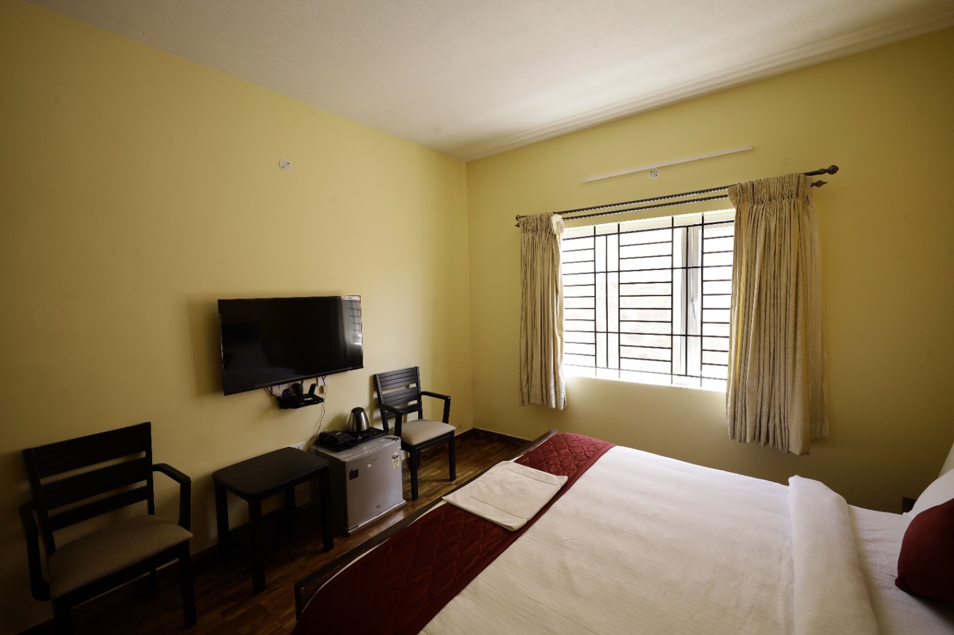 A hotel room with a bed, a desk, a chair, a television, and a window with curtains.