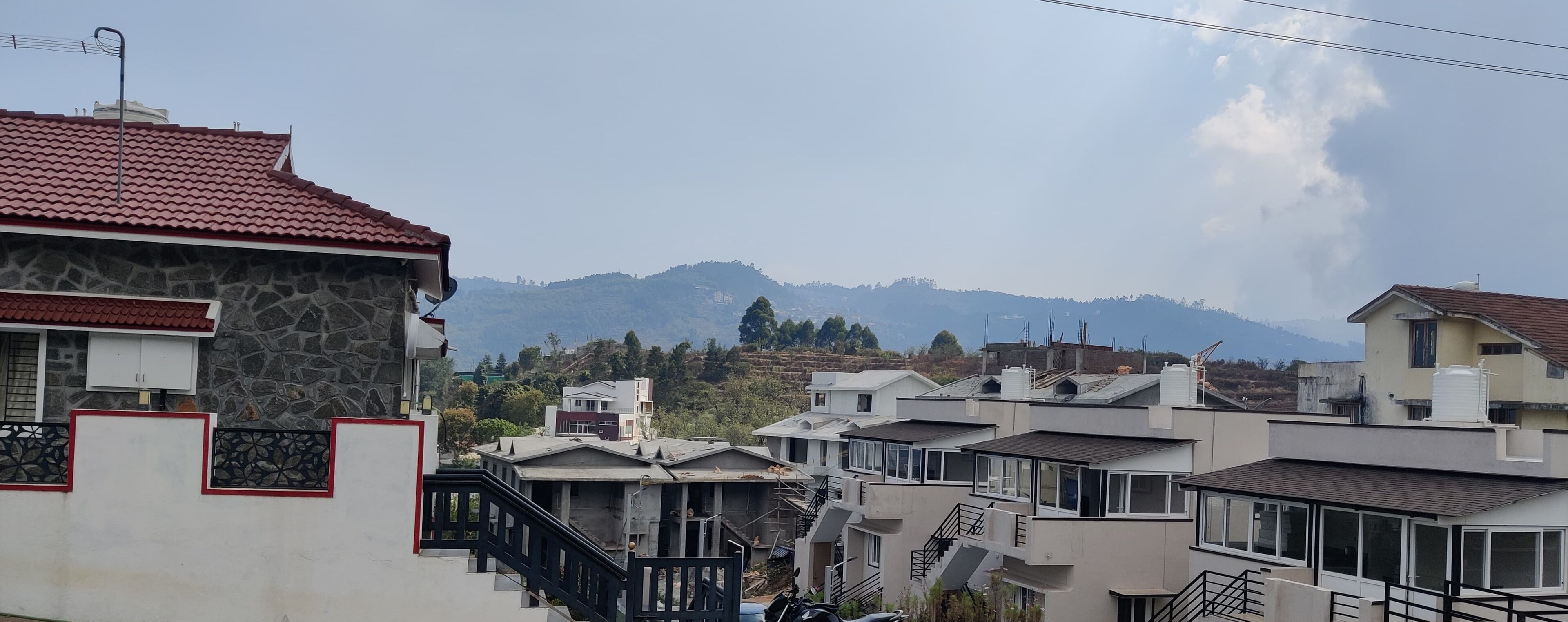A residential area with houses, a stone building, and a mountain in the background.