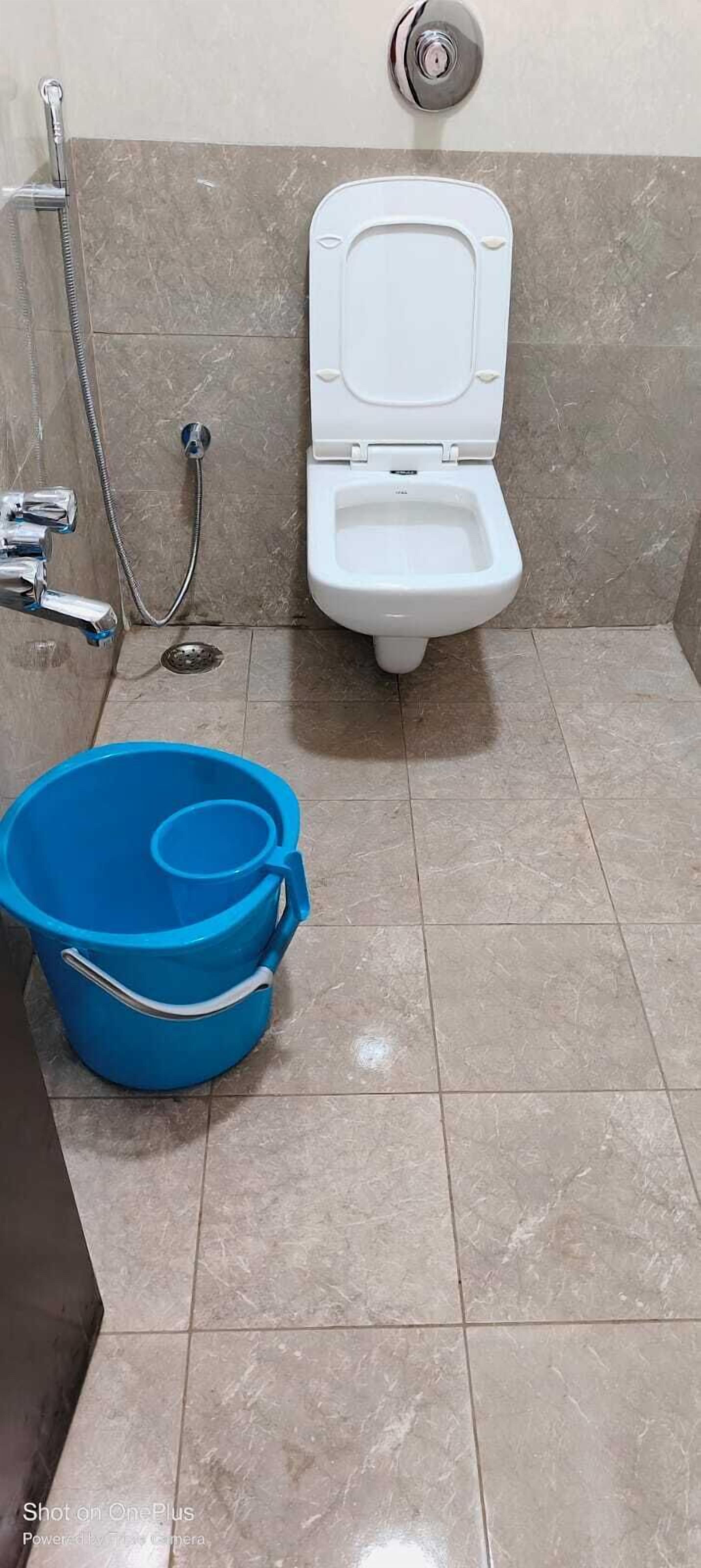Un baño con inodoro, ducha y un cubo azul.