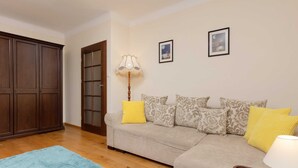Una sala de estar con sofá, alfombra azul, aparador de madera y lámpara.