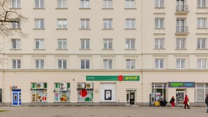 Un edificio de varios pisos con locales comerciales en la planta baja, incluyendo una tienda de comestibles y una farmacia.