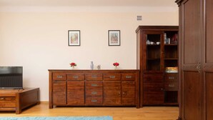 Una habitación con un armario de madera, un televisor y un tapete azul.