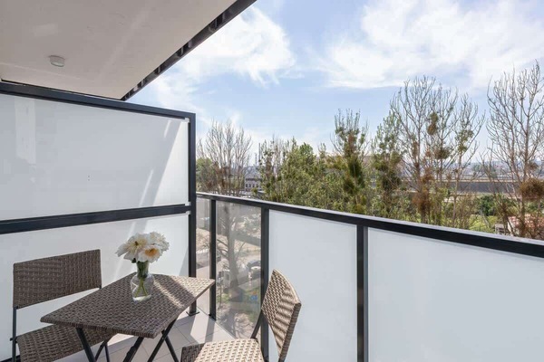 Another view of the balcony, featuring the frosted glass railings and a view of nearby trees.