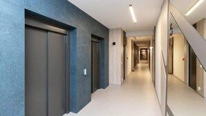 Un couloir moderne avec un mur d’accent bleu, un escalier et un long couloir menant à une porte.