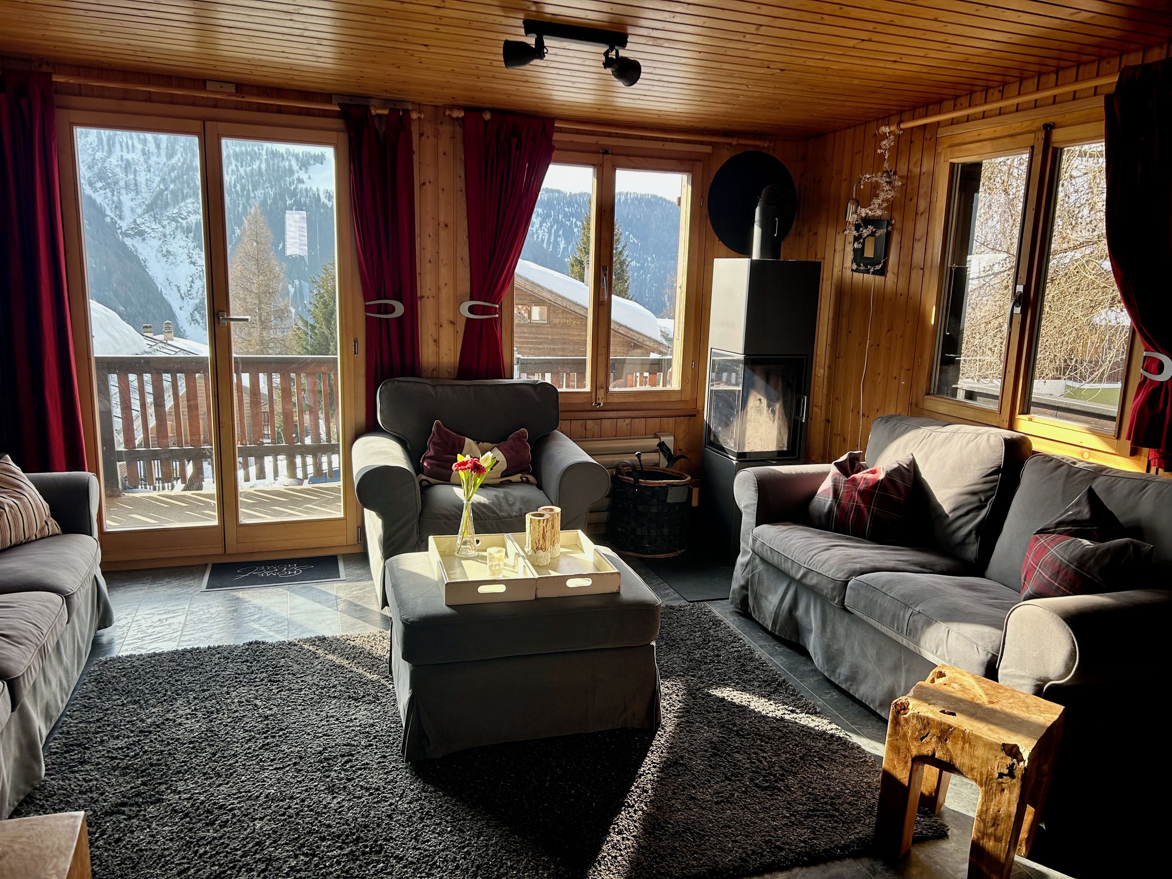 Una sala de estar acogedora con chimenea, dos sofás, una mesa de centro y vistas a una montaña nevada.