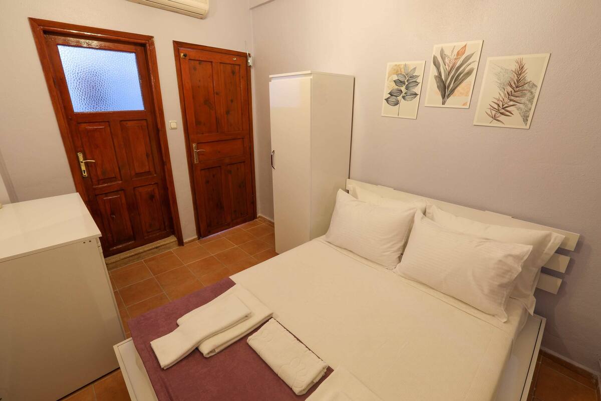 Un dormitorio con cama, dos puertas, un refrigerador y decoración en la pared.
