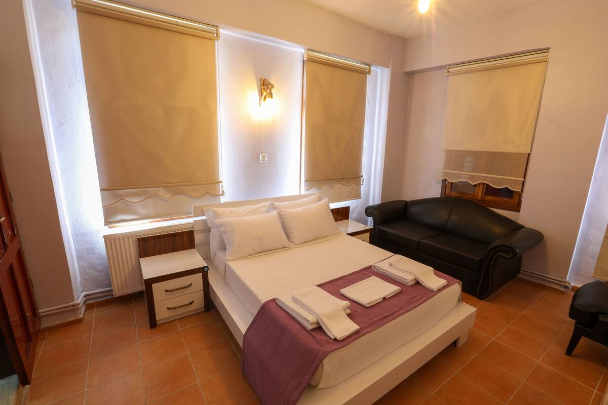 Un dormitorio con cama, escritorio, silla y ventana con cortina.