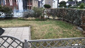 A residential area with a paved driveway, a wooden fence, and a well-maintained lawn. - Comfortable apartment with harbor view (Arzon)