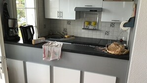 A kitchen with white cabinets, a black countertop, and a Plancha stove. - Comfortable apartment with harbor view (Arzon)
