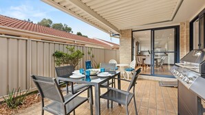 Une terrasse extérieure équipée d’un barbecue, d’une table à manger et de chaises.