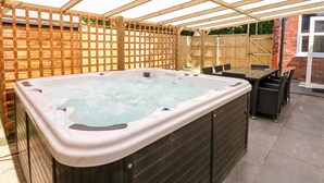 A hot tub under a wooden pergola in a backyard. - The Beach House (Mablethorpe)