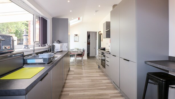 A modern kitchen with a long island, stainless steel appliances, and a view of the outdoors. - The Beach House (Mablethorpe)