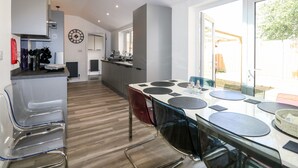 A modern kitchen with a dining area, featuring a large window, a built-in oven, and a clock on the wall. - The Beach House (Mablethorpe)