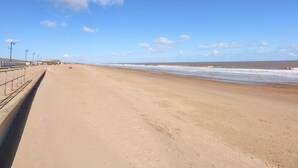 A wide sandy beach with a clear sky and a few clouds. - The Beach House (Mablethorpe)