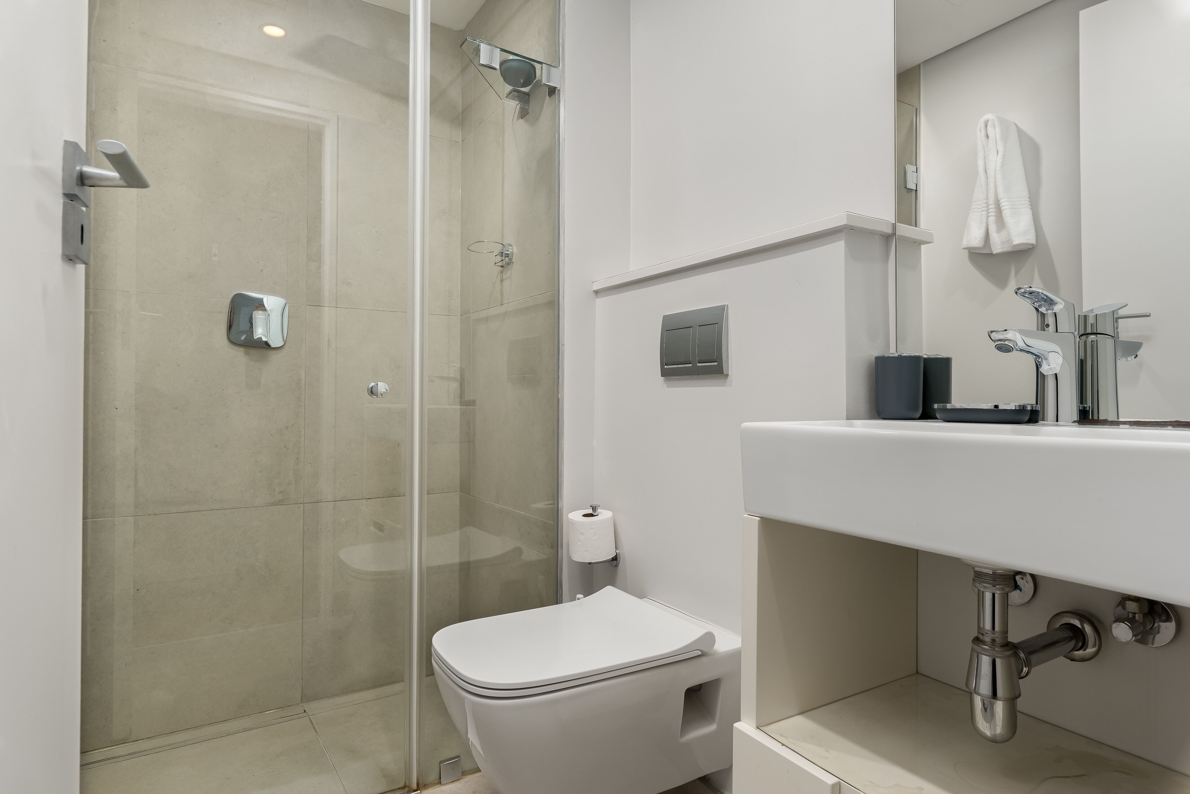 A modern bathroom with a glass-enclosed shower, a white toilet, and a sink with a mirror above it.