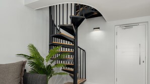 A modern interior with a curved staircase, a potted plant, and a white door. - TenOnQ B4 (Cape Town)