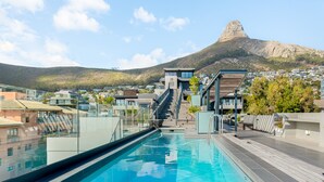 A swimming pool with a view of a mountain and residential buildings in the background. - TenOnQ B4 (Cape Town)