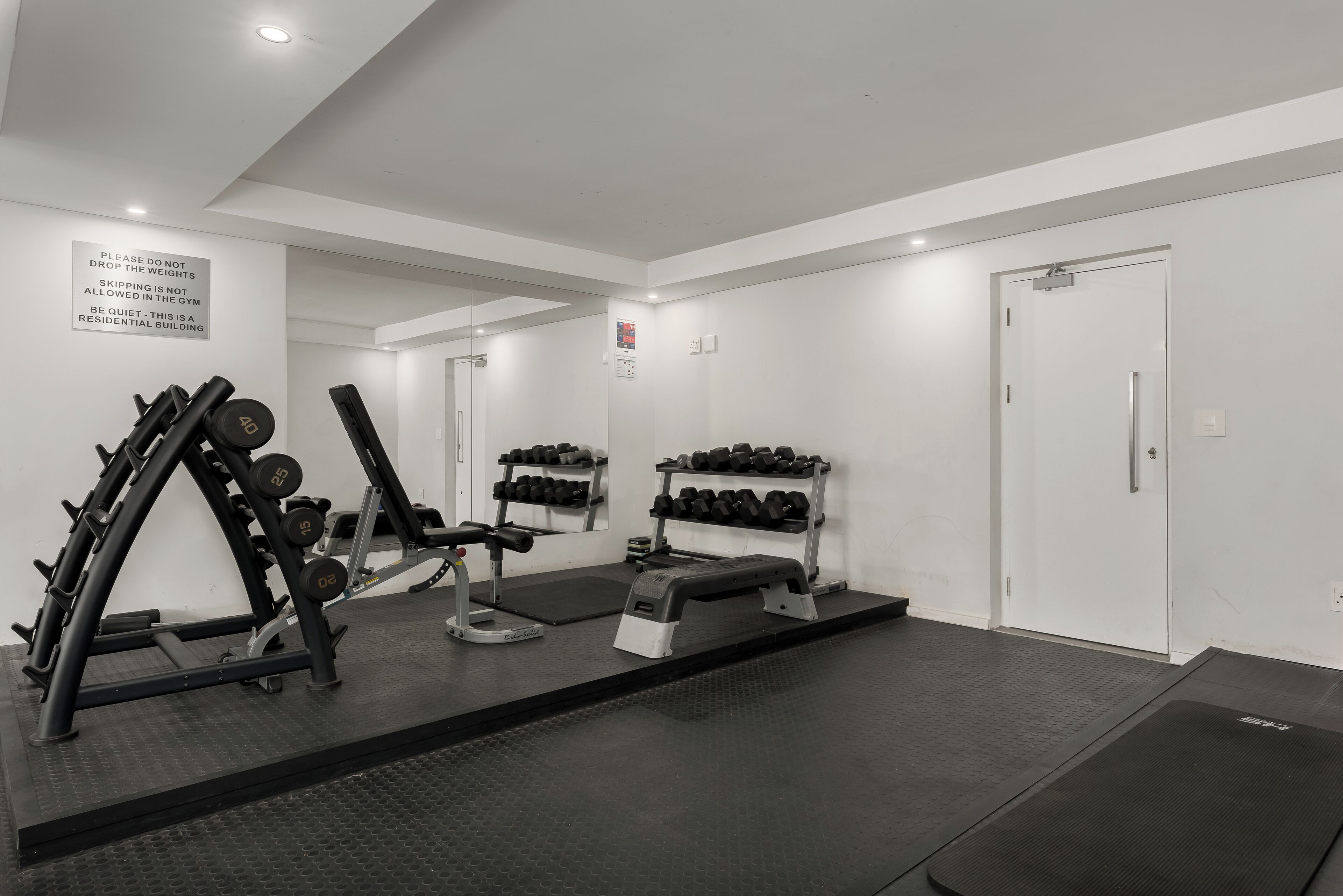 Una palestra con attrezzature per l'allenamento con i pesi, manubri e una panca.