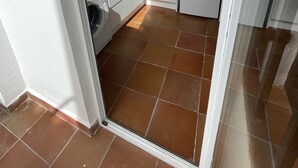 Ett kompakt kök med vita skåp, en mikrovågsugn, ett kylskåp och en tvättmaskin.