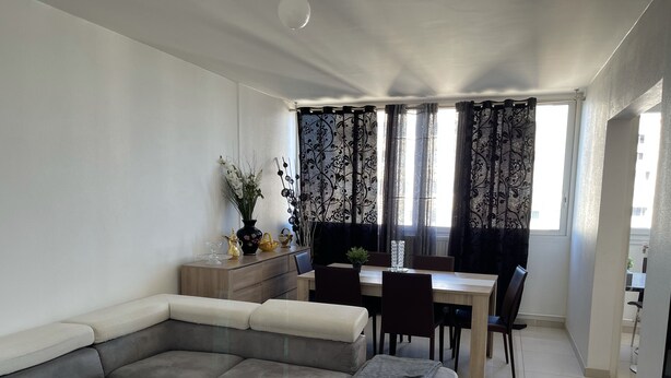 Una sala moderna con un sofá modular, una mesa de comedor y una pequeña cocina.