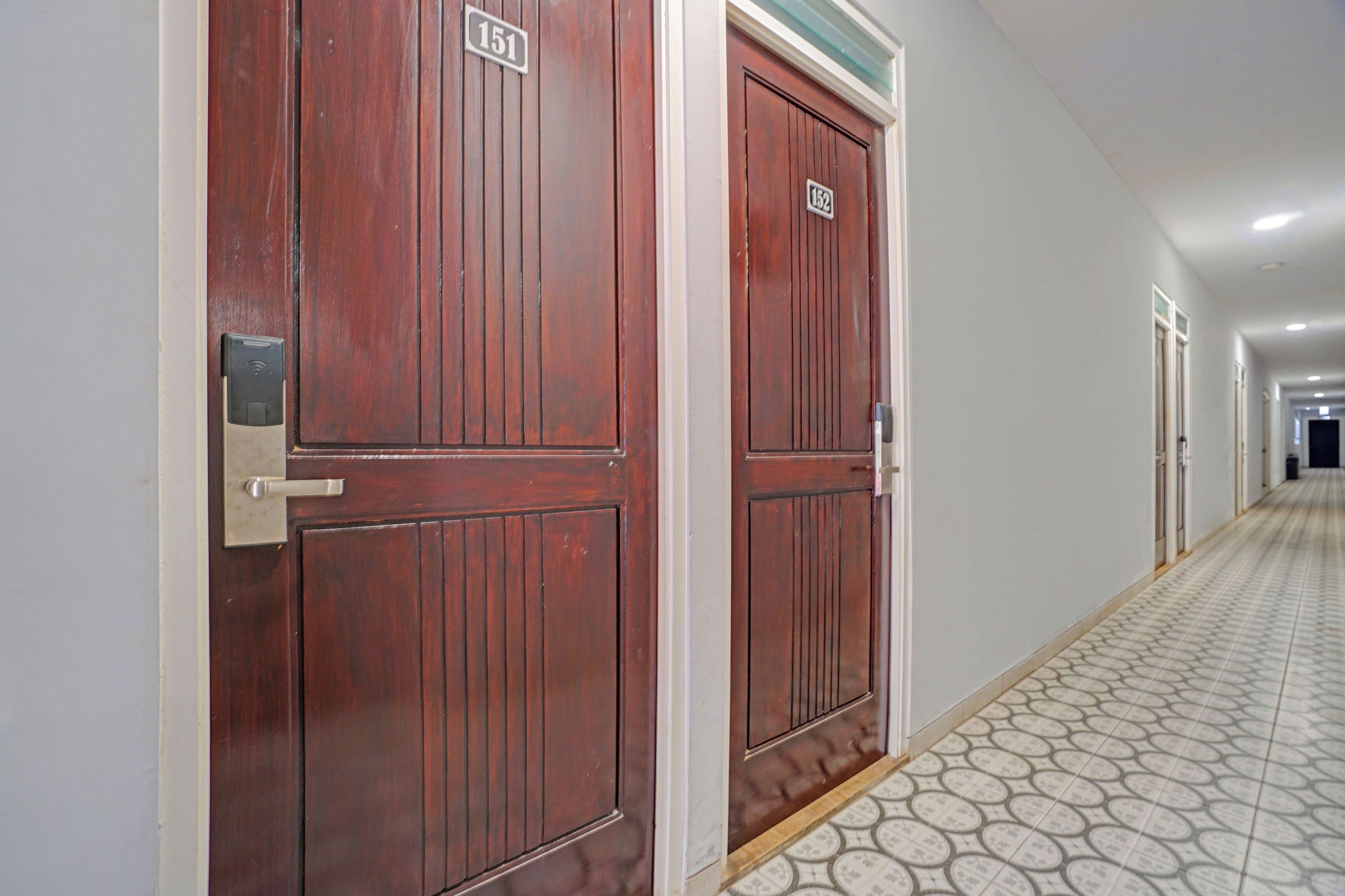 A hallway with two wooden doors, each marked with a number. The floor has a patterned tile design.