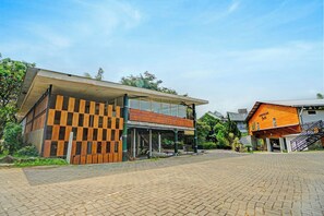 Un edificio moderno con fachada a cuadros, una zona exterior cubierta y una escalera que conduce a un segundo nivel.
