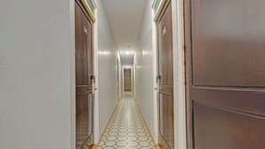 Um corredor com chão estampado, portas de madeira e parede em tom claro.