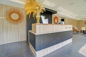 Una recepción con diseño moderno, que presenta un acabado de madera y un motivo decorativo de sol en la pared.