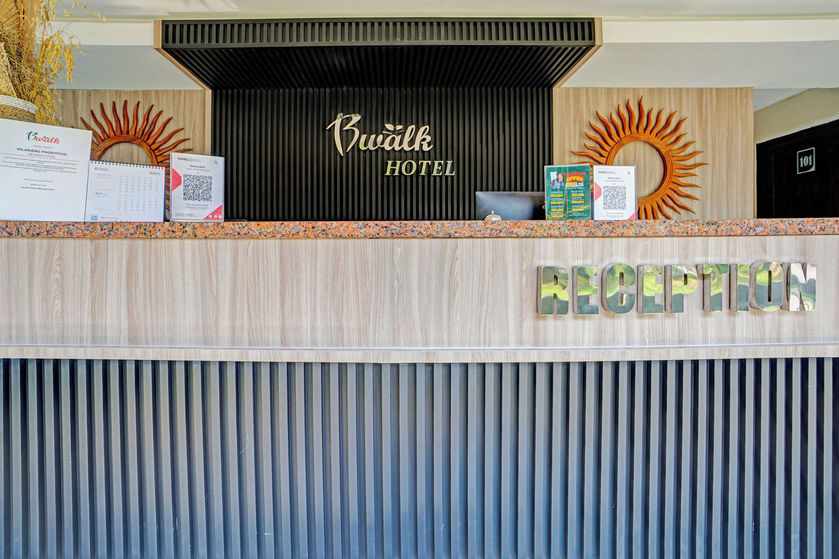 Una reception di hotel con pannelli in legno, una insegna della reception e una decorazione solare a parete.