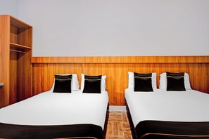 Ein Hotelzimmer mit zwei Betten, einem Holzkopfende und einem eingebauten Kleiderschrank.