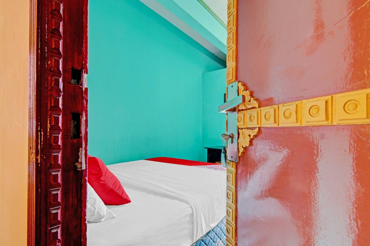A room with a bed, a door, and a wall painted in teal and red.