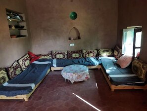 A cozy room with a sofa set, a small table, and a mirror on the wall. - Jardin D'hôtes Privatif Dans le Désert (Mhamid)