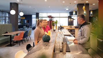 Zona de bar moderna con una barra larga, asientos y vistas al área del restaurante.