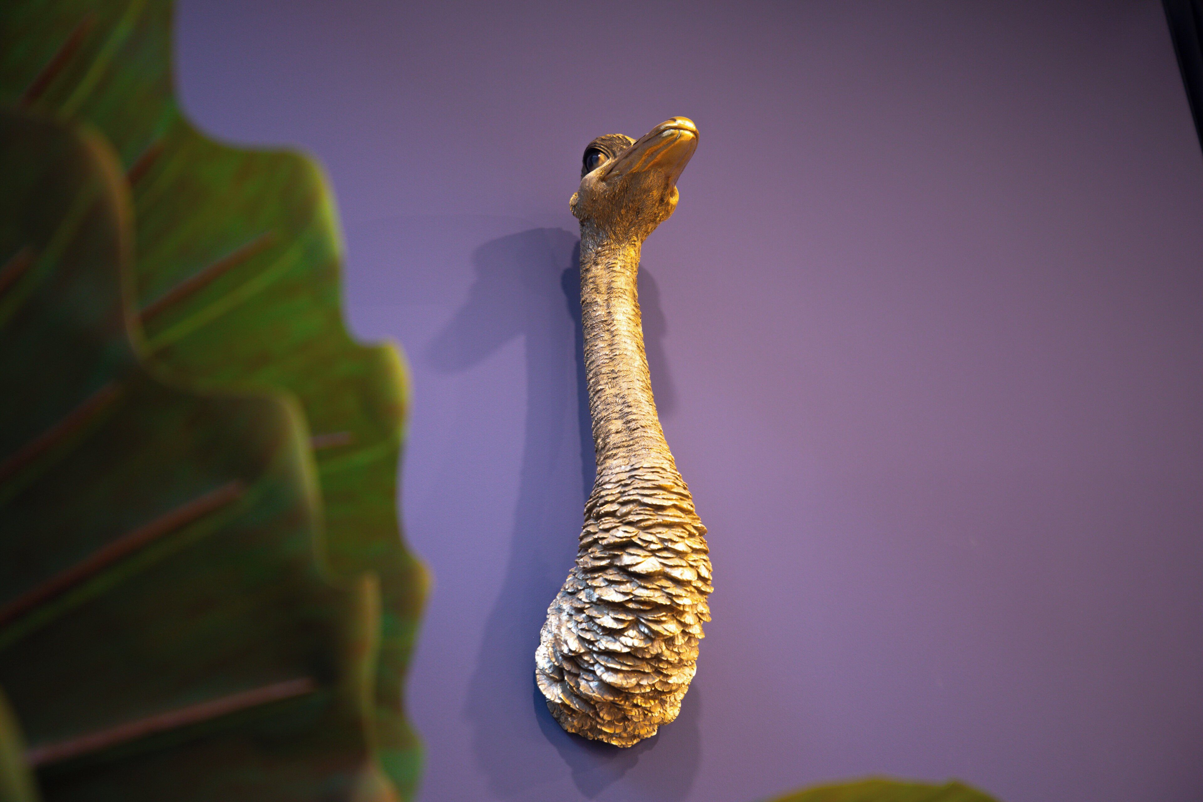 Um artefato dourado com superfície texturizada, possivelmente um objeto decorativo, sobre fundo roxo.