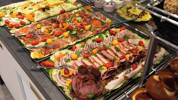 A buffet with various food items including meats, cheeses, and fruits.