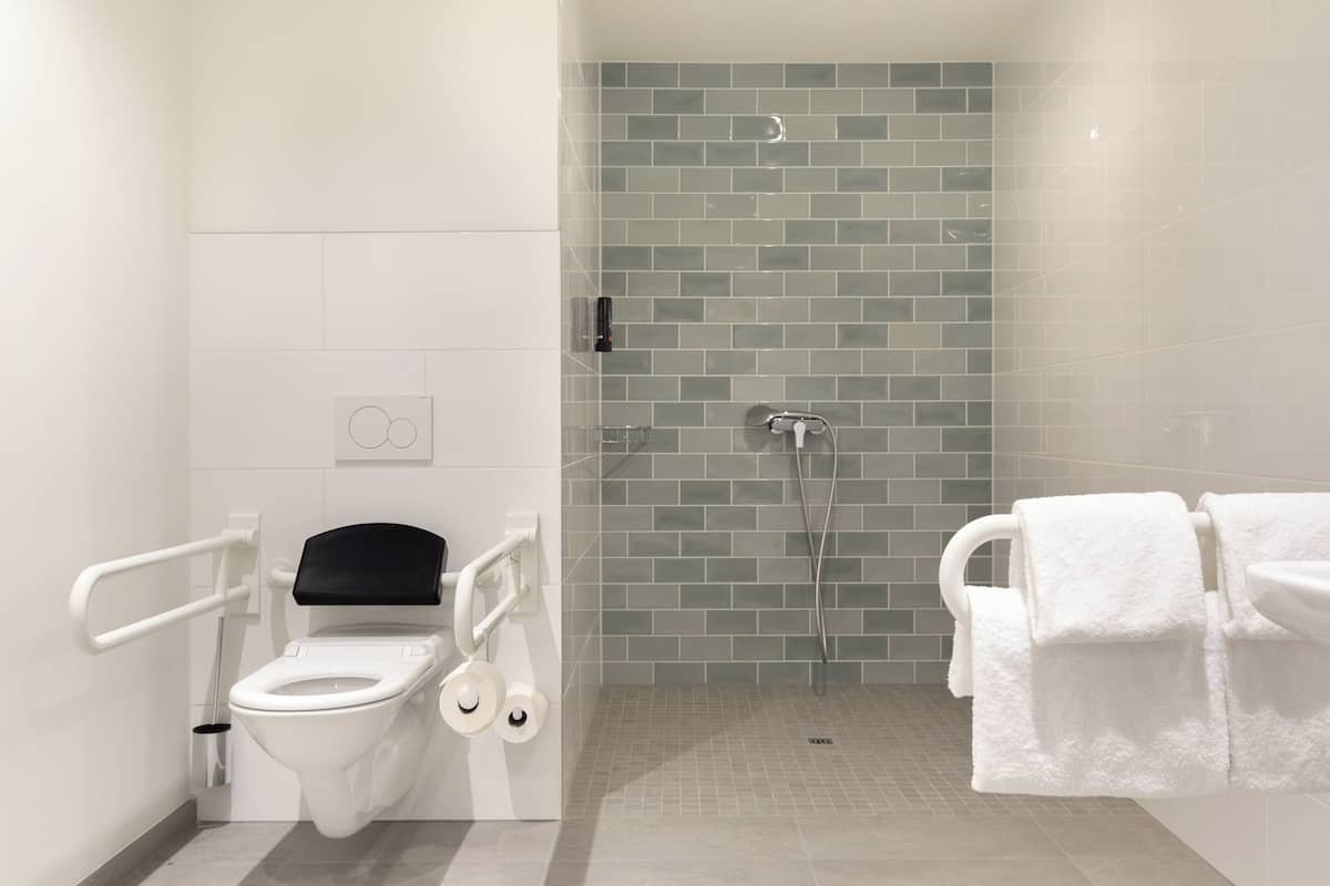 Un baño moderno con inodoro, ducha y lavamanos con toallas.