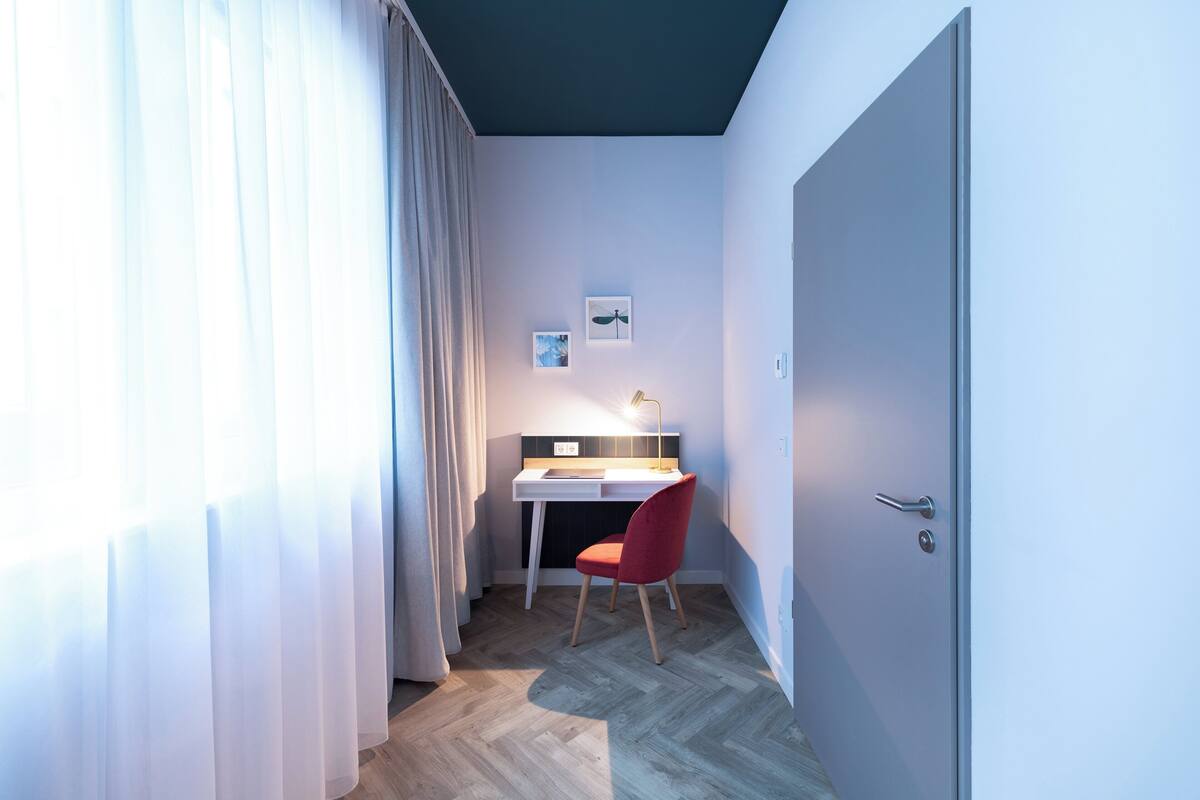 Una habitación pequeña y moderna con escritorio, silla y puerta.