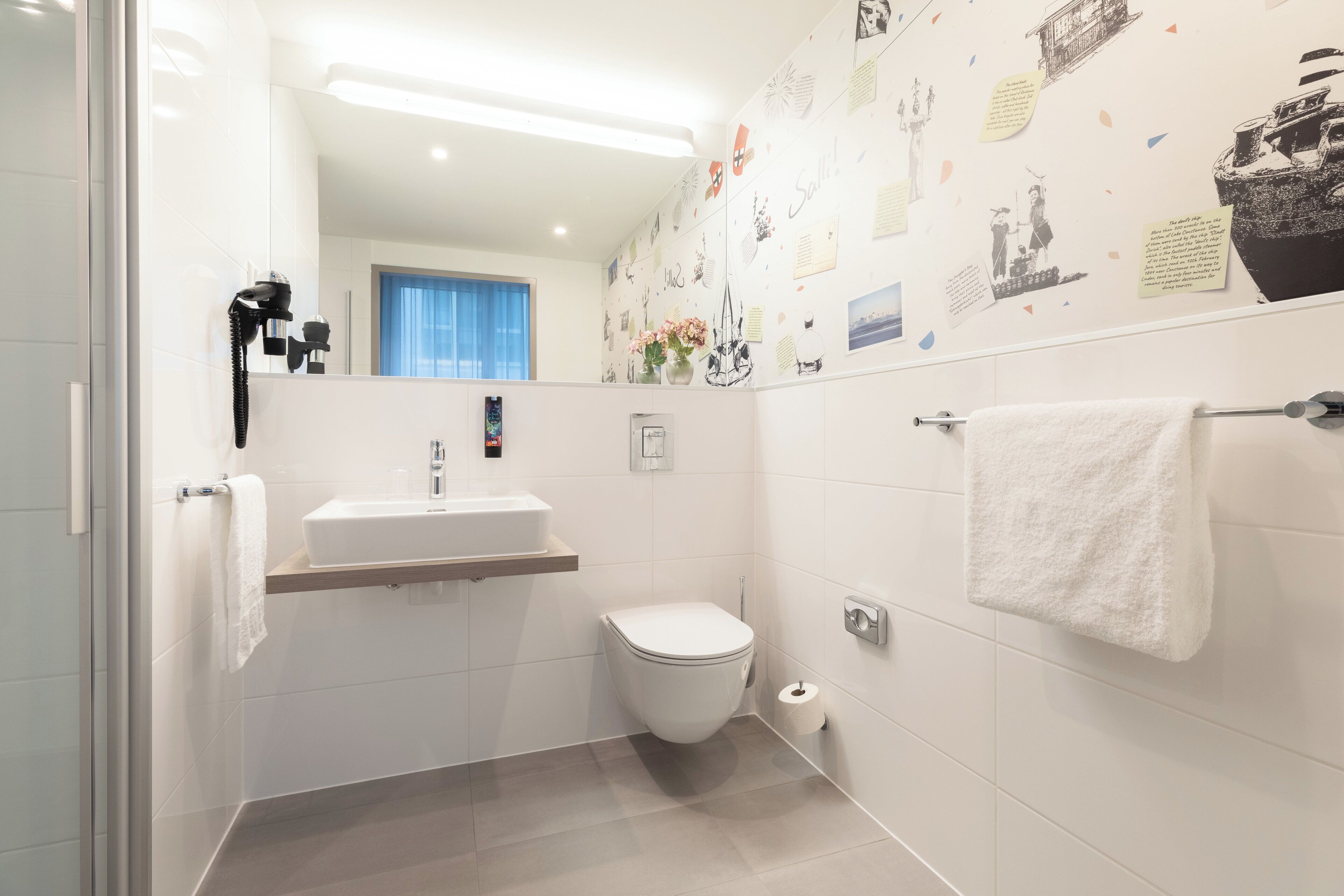 Une salle de bain moderne équipée de toilettes, d’un lavabo et d’un porte-serviettes.