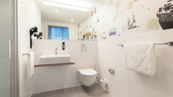 Une salle de bain moderne équipée de toilettes, d’un lavabo et d’un porte-serviettes.