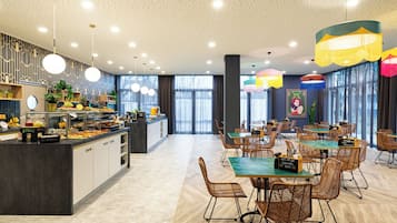 A modern dining area with a buffet, wicker chairs, and pendant lighting.