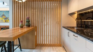 A modern kitchen with a wooden partition, a dining table with chairs, and a painting on the wall. - LF PARKING INCLUDED. Loft adjacent to Santa Cruz (Sevilla)