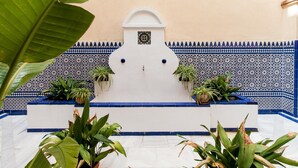 Un cortile con un muro bianco, piastrelle a motivi blu e bianchi e piante in vaso.