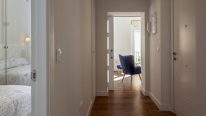 Un pasillo con piso de madera que conduce a un balcón con una silla azul.