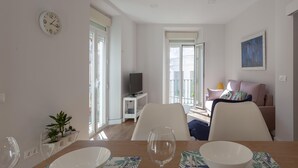Una sala de estar moderna con comedor, televisión y un balcón con vistas.