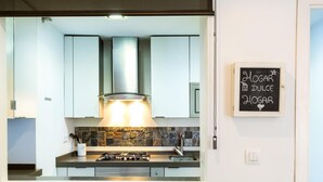 A modern kitchen with a gas stove, stainless steel cabinets, and a stone backsplash. There is a chalkboard on the wall with the text "Hogar dulce hogar." - LR2 PRIVATE TERRACE and parking included. Apartment in the Historic Center (Sevilla)