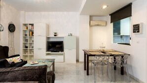 A modern living room with a sofa, a coffee table, a TV, and a bookshelf. - LR2 PRIVATE TERRACE and parking included. Apartment in the Historic Center (Sevilla)