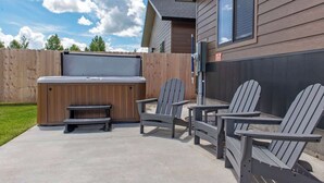 Ein Garten mit Whirlpool, Adirondack-Stühlen und Holzpforte.