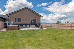 A single-story building with a flat roof, a covered patio area with outdoor furniture, and a wooden fence surrounding the property.
