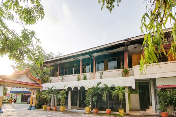 A two-story building with a tiled facade, a covered entrance with a red roof, and multiple potted plants. - OYO 2690 Hotel Tampan (Pekanbaru)
